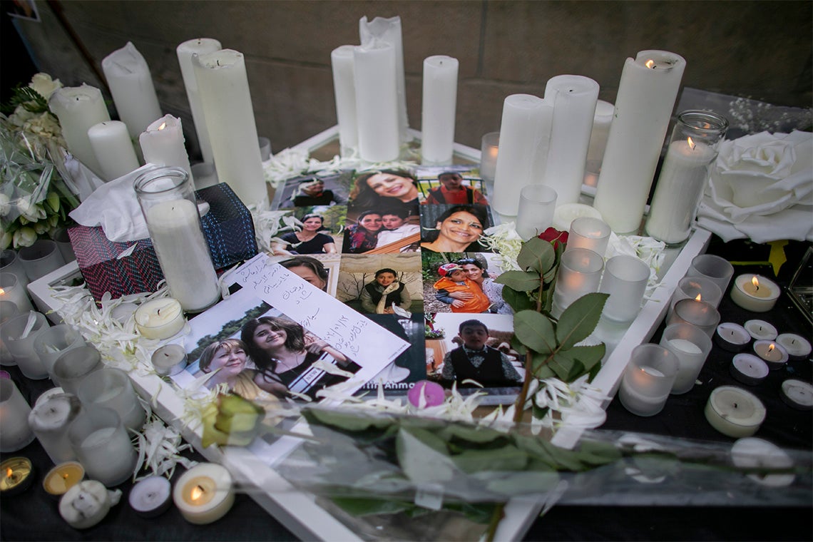 a table with lit candles, flowers and photos of the victims of the PS752 plane crash