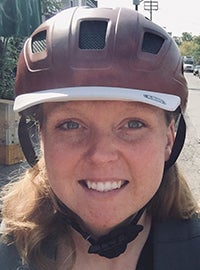 Karina Maynard wearing a bike helmet. A typical downtown Toronto street is in the background
