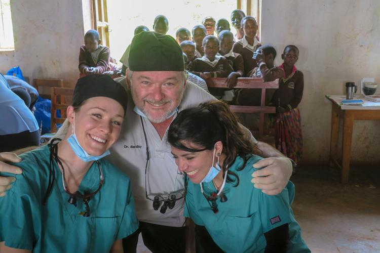 Izchak Barzilay laughing with dentistry students in Uganda as locals look on in the background