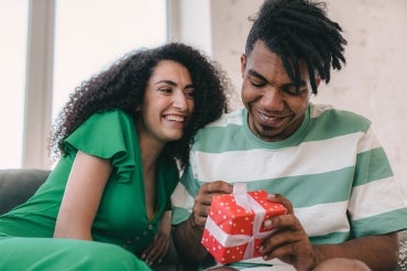 A man opens a gift received from his partner