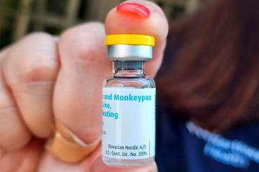 a person holds up a vial of monkeypox vaccine
