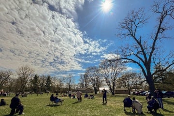 several people sit in a park to view the 2024 total eclipse in Chiefswood Park