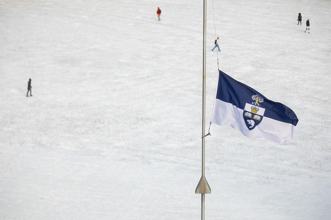 U of T flag at half-mast with a snowy field in the background