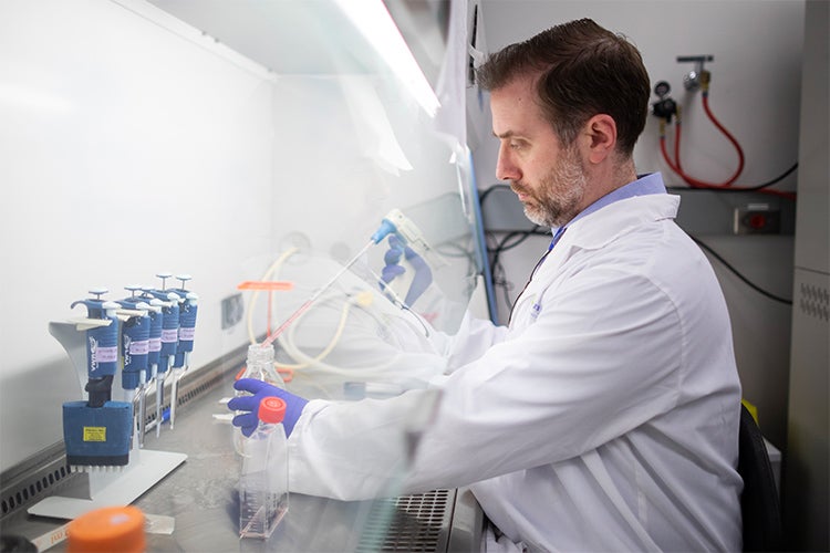 Robert Kozak working with chemicals behind a glass fume hood window