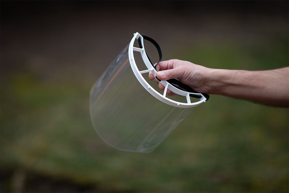 A reusable plastic face shield is held up on display
