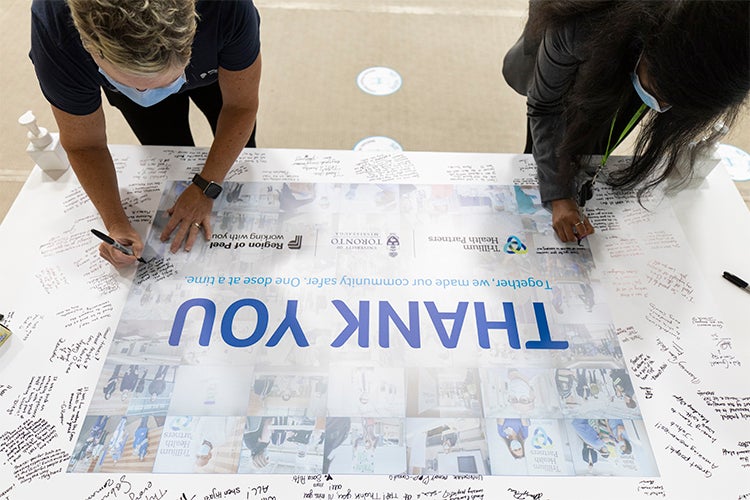 Two people are seen signing the thank you board at the UTM vaccination clinic