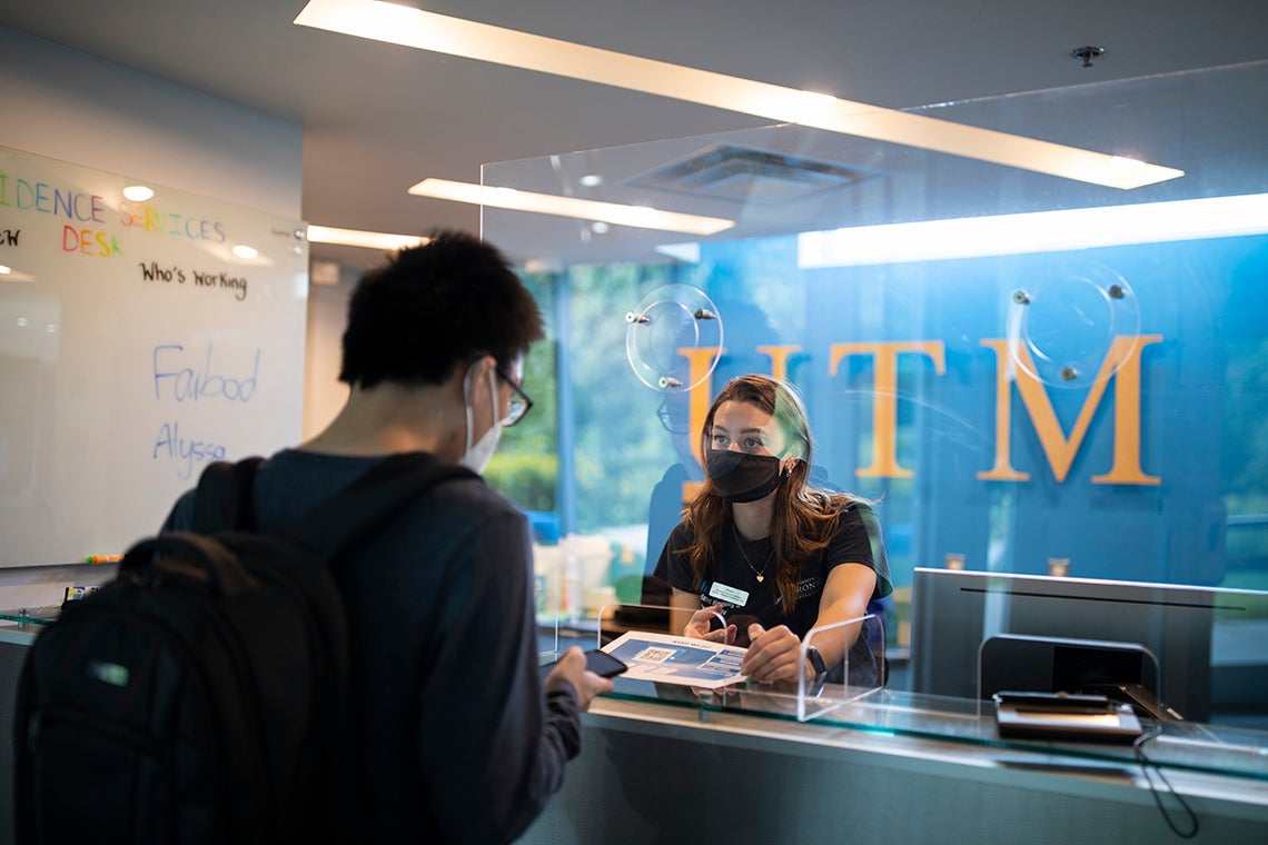 A staffer helps a new student check into residence at UTM