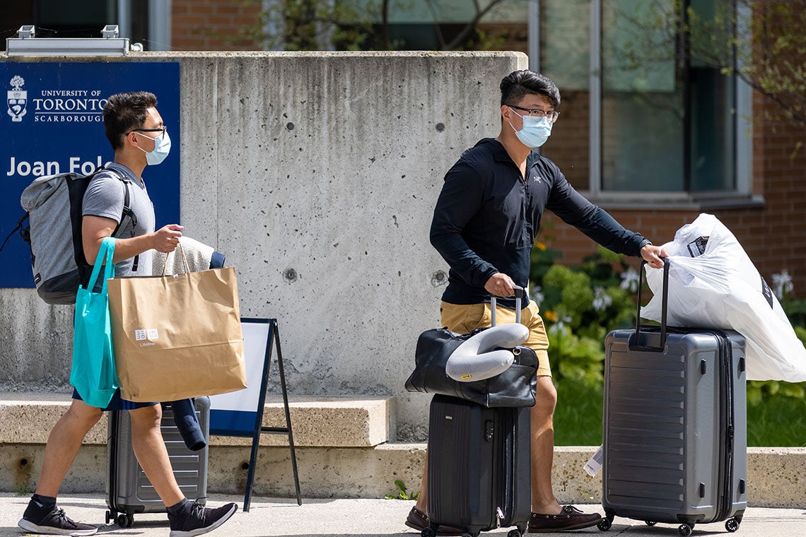 two male students carrying bags and pushing luggage as they move into residence at the University of Toronto Scarborough campus