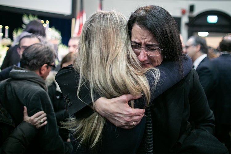 A woman cries while hugging another woman inside convocation hall