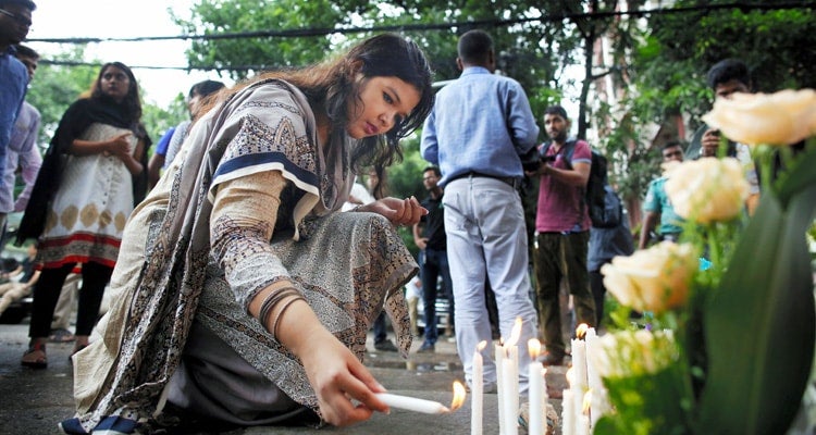 photo of woman lighting candle at Dhaka memorial