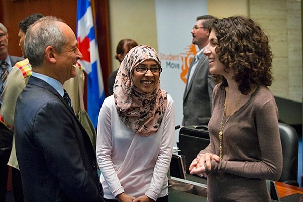 A photo of two students talking to President Gertler