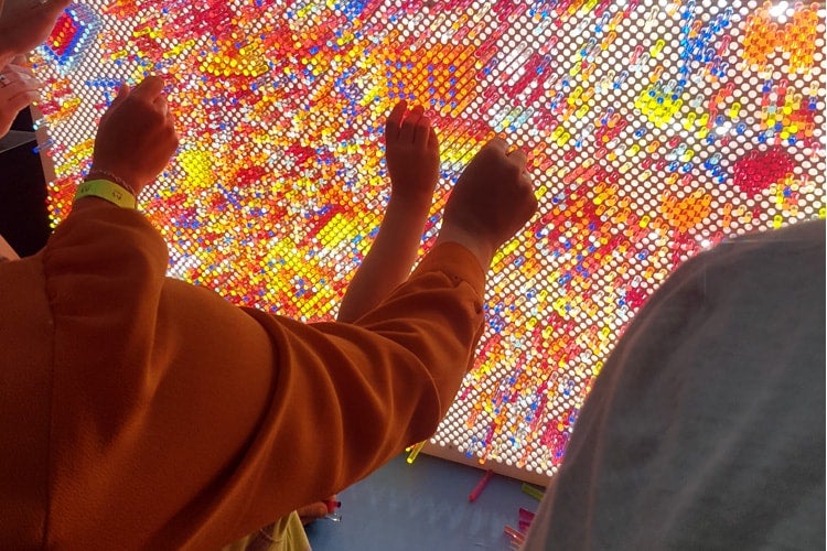 photo of hands working on what looks like a giant Lite Brite board