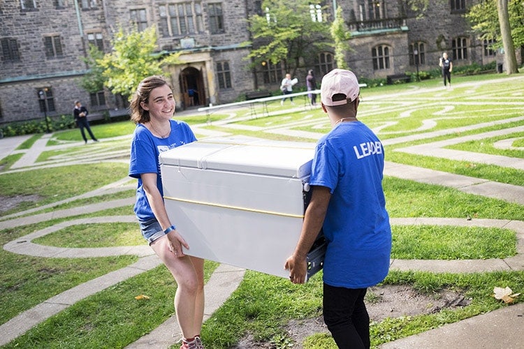 Student leaders carrying mini fridge across quad