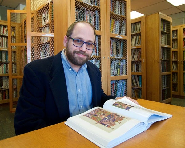 photo of Cohen sitting at table with his book open in front of him