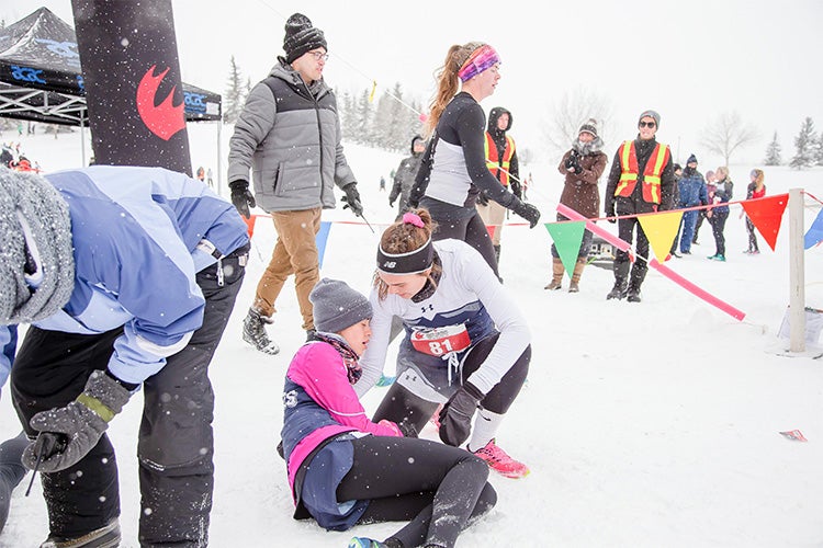 Julia Costanzo helps a teammate at the finish line at Grande Prairie, Alberta