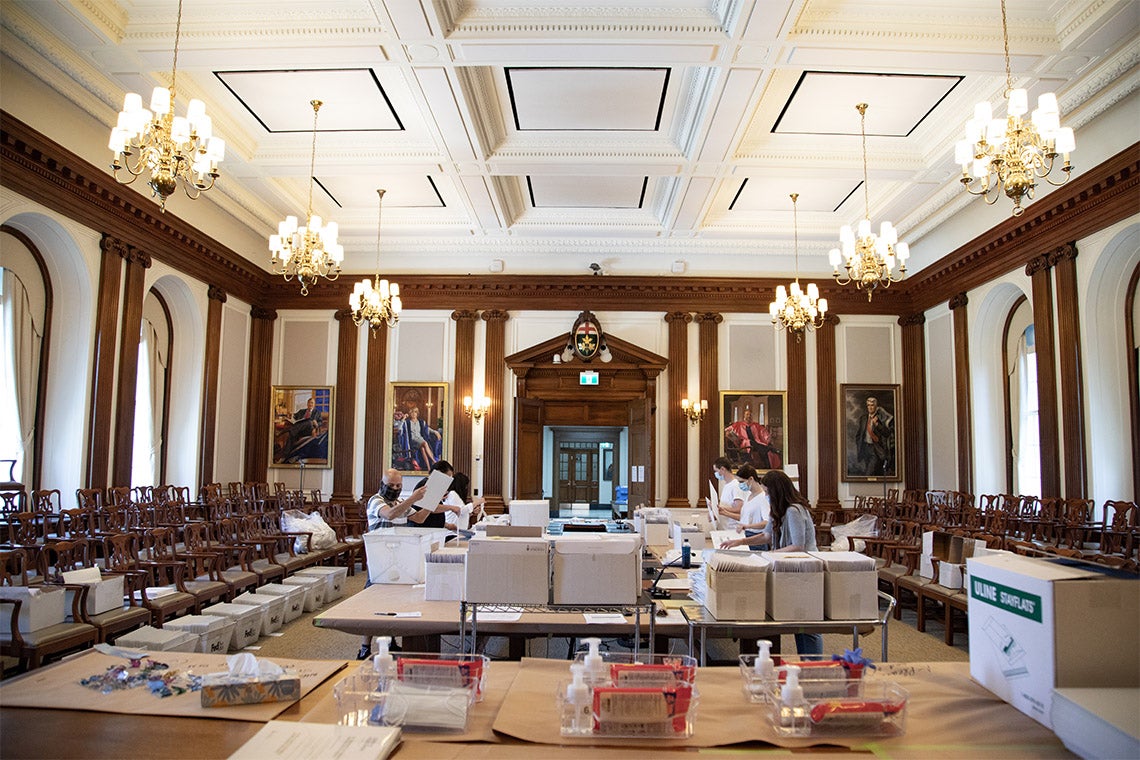 volunteers stuff degrees into envelopes at simcoe hall