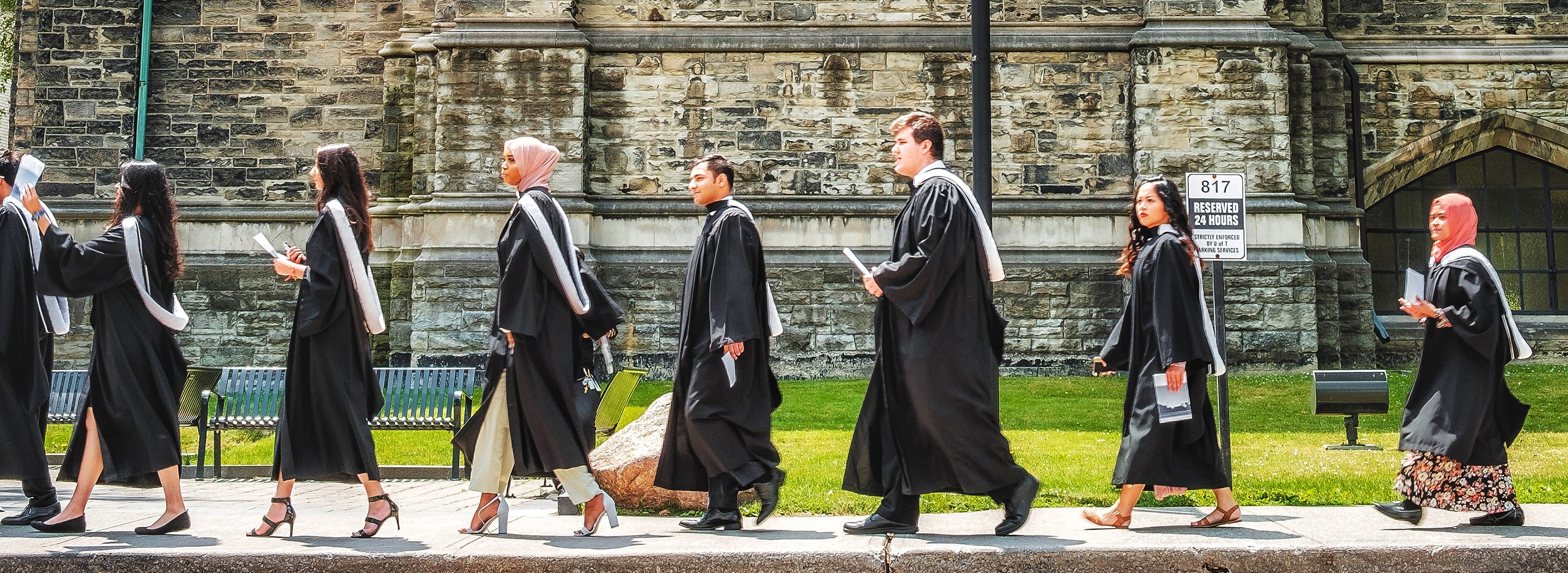 A group of U of T graduates walking in regalia.