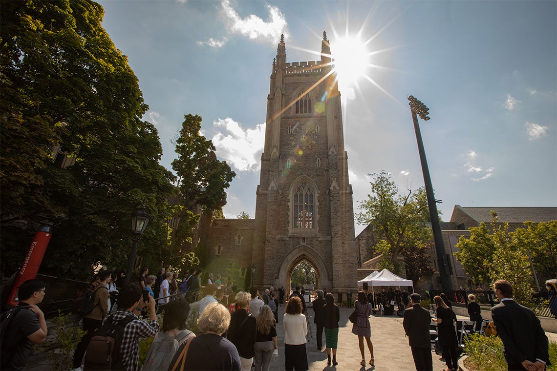 a wide shot of the crowd listening the the tolling bells outside soldier's tower during the ceremony