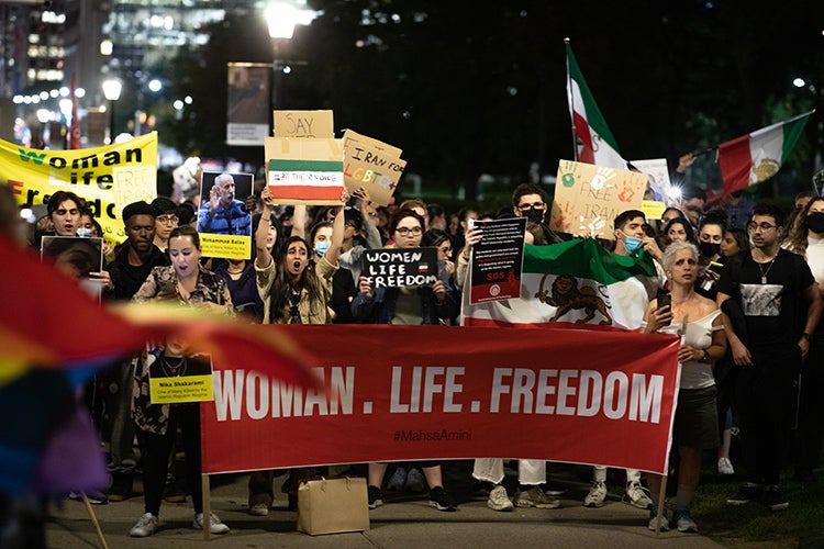 Protestors wave signs at a rally in Toronto to protest the death of Mahsa Amini