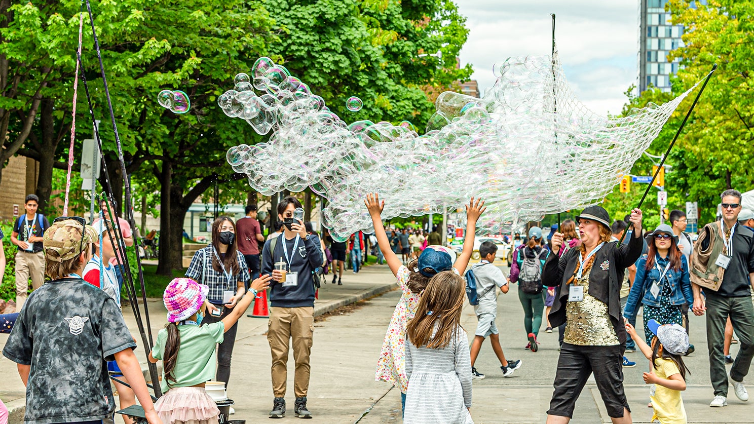 a street performer makes soap bubbles on the street during alumni fest
