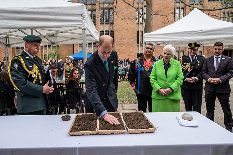 The Duke of Edinburgh sprinkles seeds of Chapel Royal Tobacco in soil 