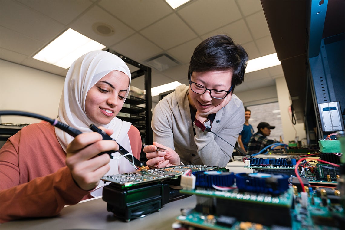 two women in a lab at the University of Toronto working on a printed circuit board 