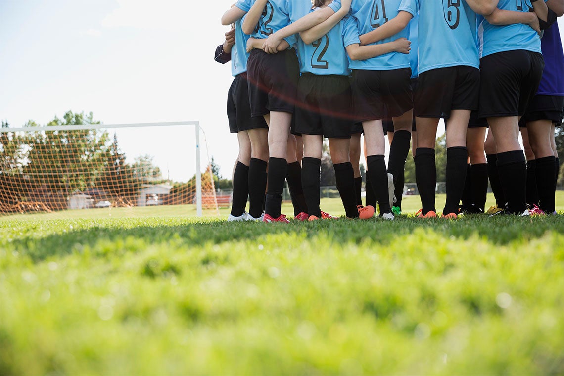 A group of young female soccer players in a huddle