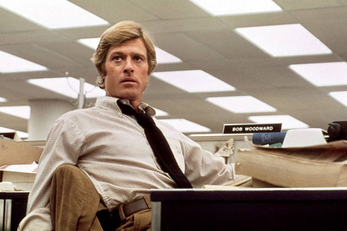 Robert Redford as Bob Woodward sits at a desk in a still from the movie All the President's Men