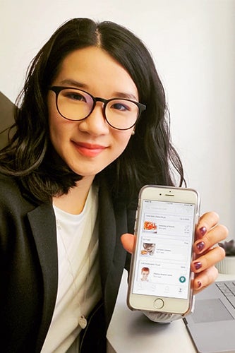 Co-founder Catherine Chan holds up an iphone with the Honeybee Hub App shown