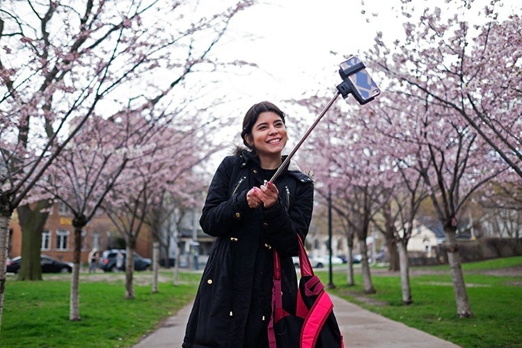 A photo of Sofia Vitorino, an ESL student, taking a selfie amid cherry blossoms