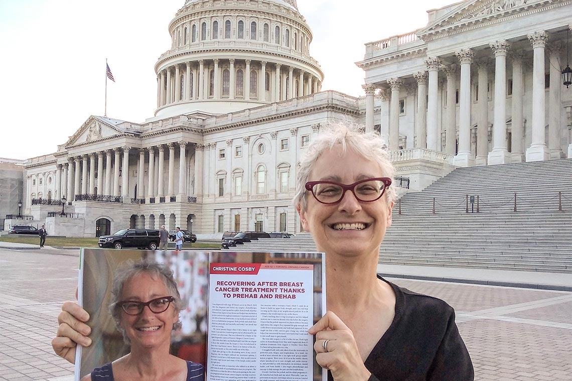 Christine Crosby in Washington, DC standing in front of the capitol buildings holding up a magazine with a story about her