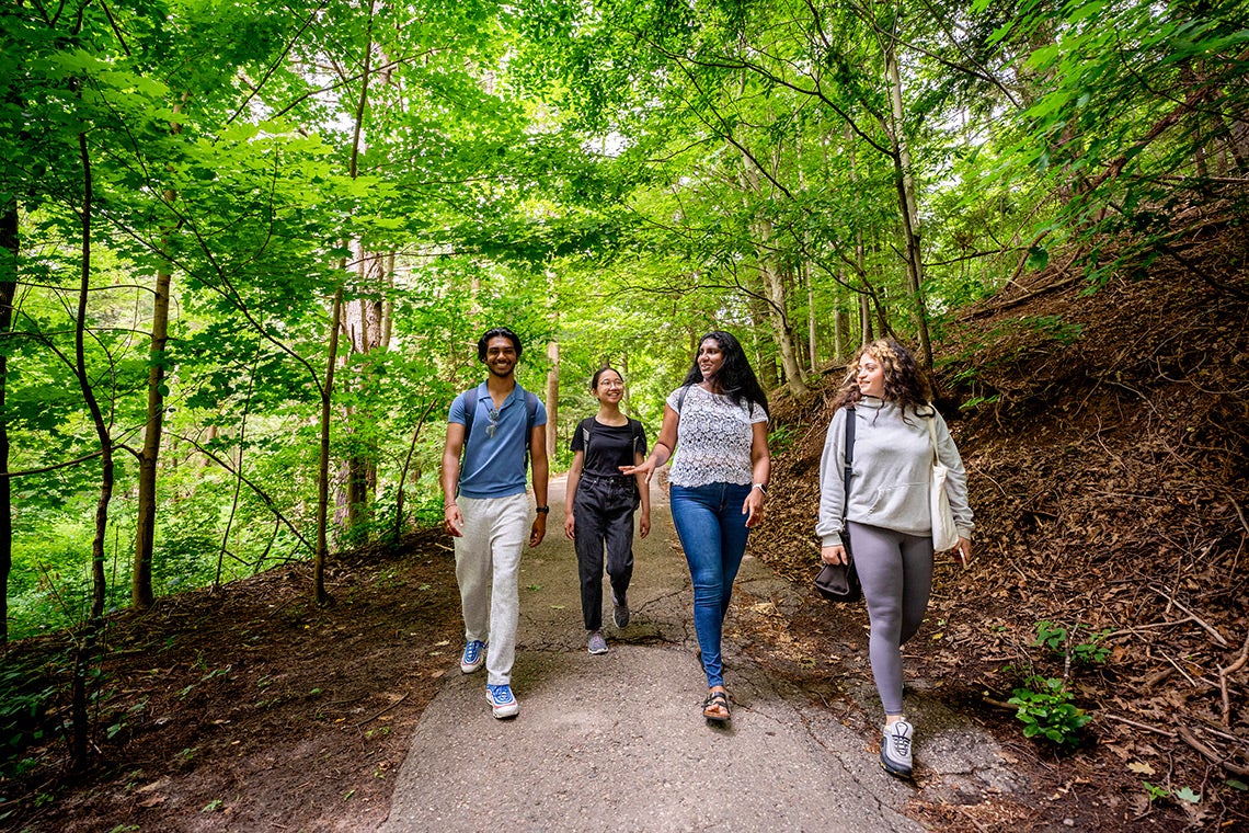 4 students walk together through the land valley trail at U of T Scarborough