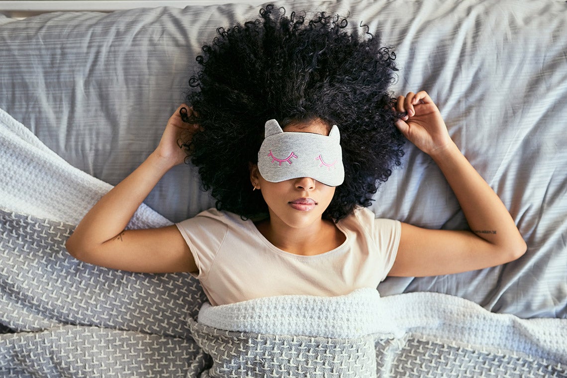 Photo of a woman lying in bed with an eye mask on