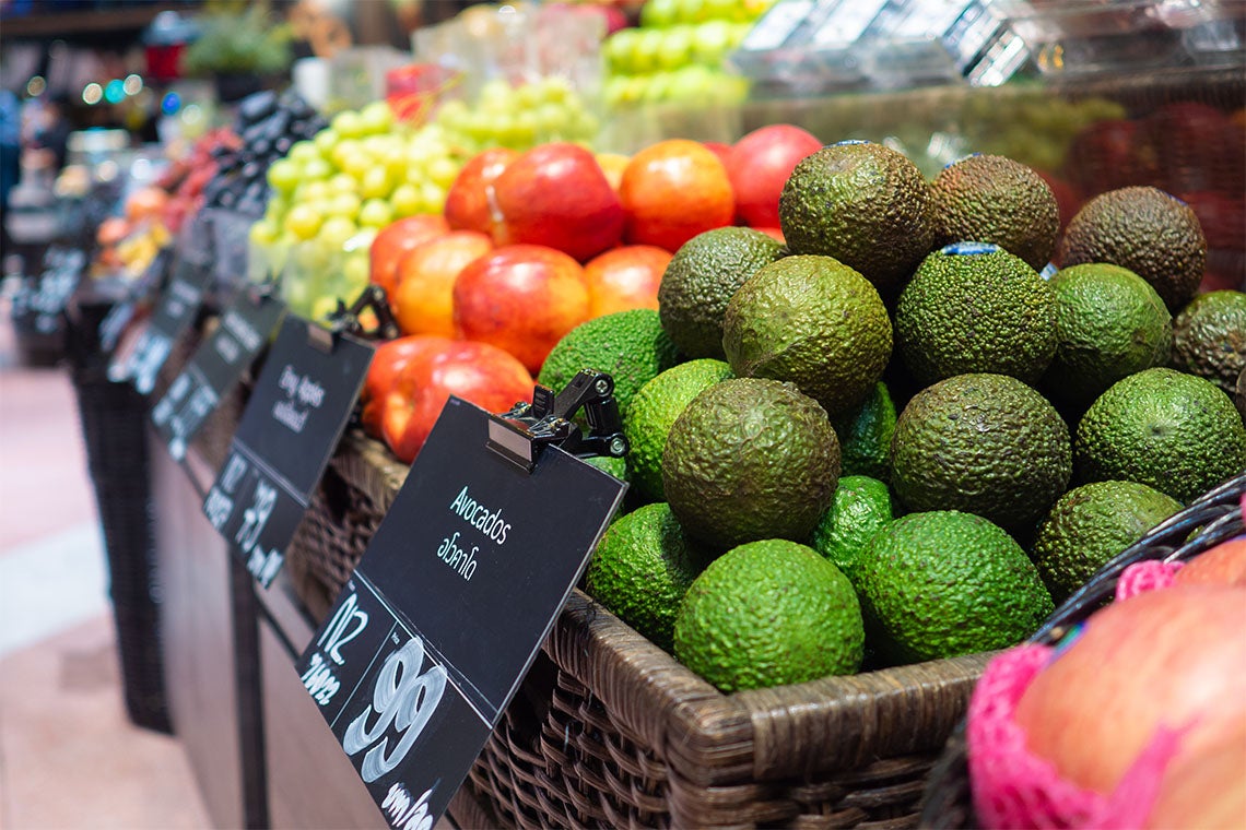 Avocados and tomatoes are piled high at a supermarket