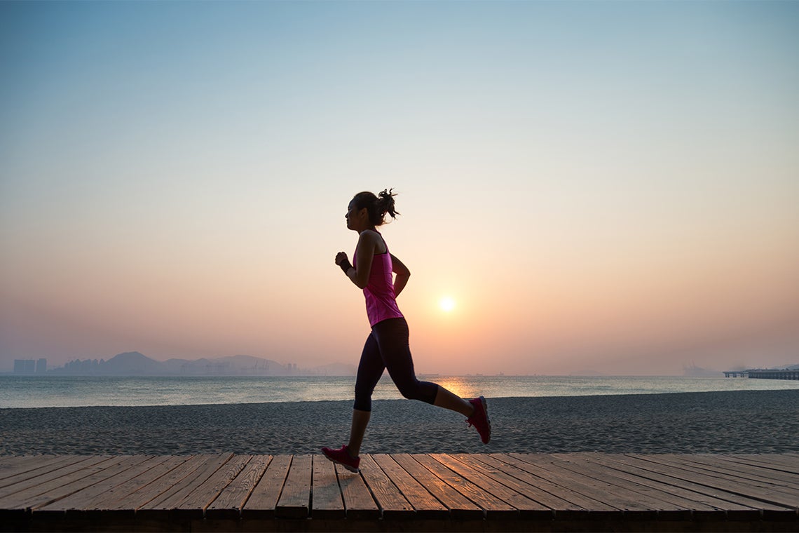 a young woman jogs along the boardwalk at sunrise