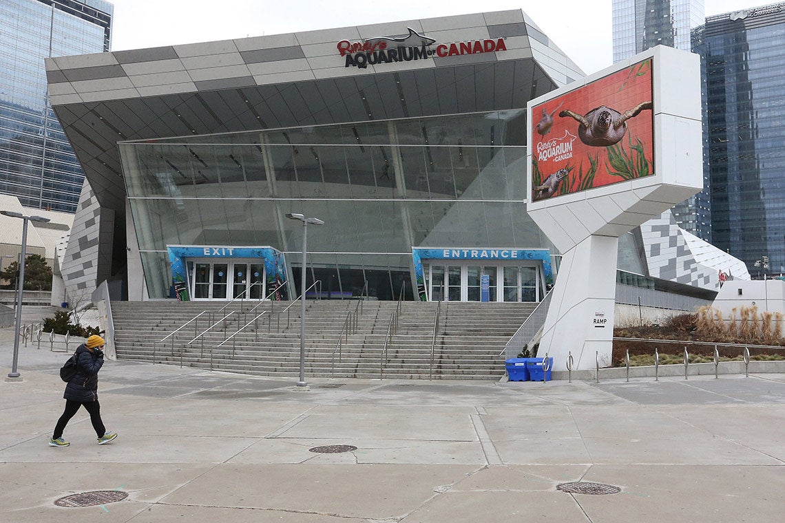 A pedestrian walks in front of an empty Ripley's Aquarium in downtown Toronto