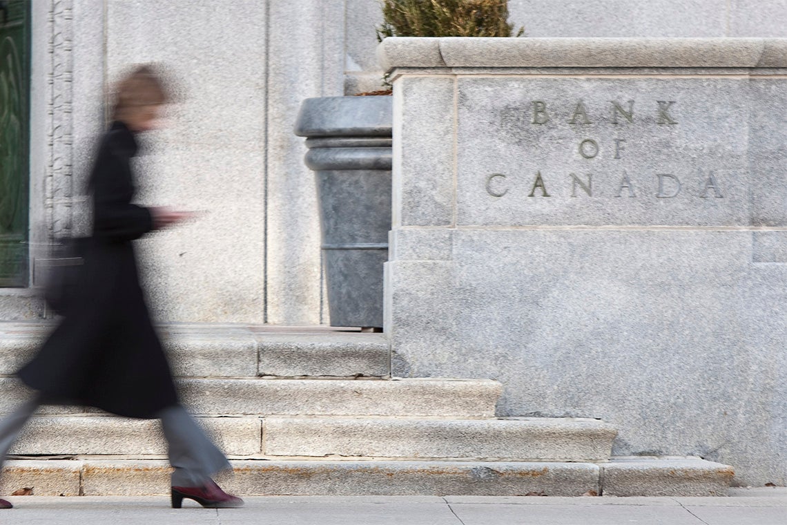 A woman walks past the front entrance of the bank of canada