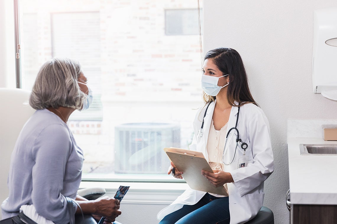 doctor advising a senior patient. Both are masked