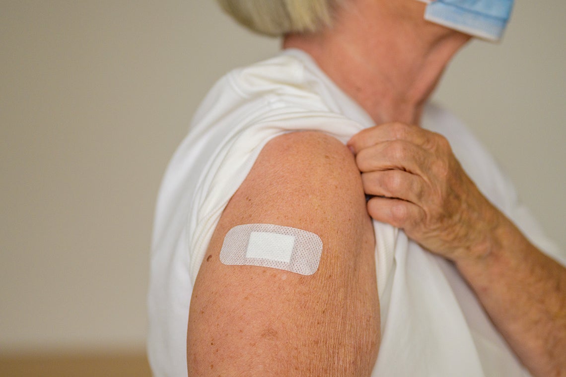 an elderly woman with a band aid on her arm after being vaccinated