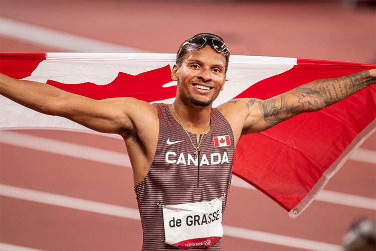 Andre de Grasse hold up a canadian flag after winning the 200m final race at the Tokyo 2020 olympics