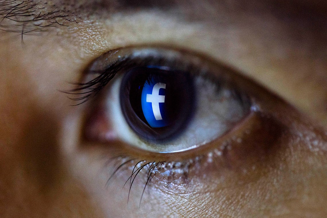 close up photo of a person's eye with the Facebook logo reflected in it