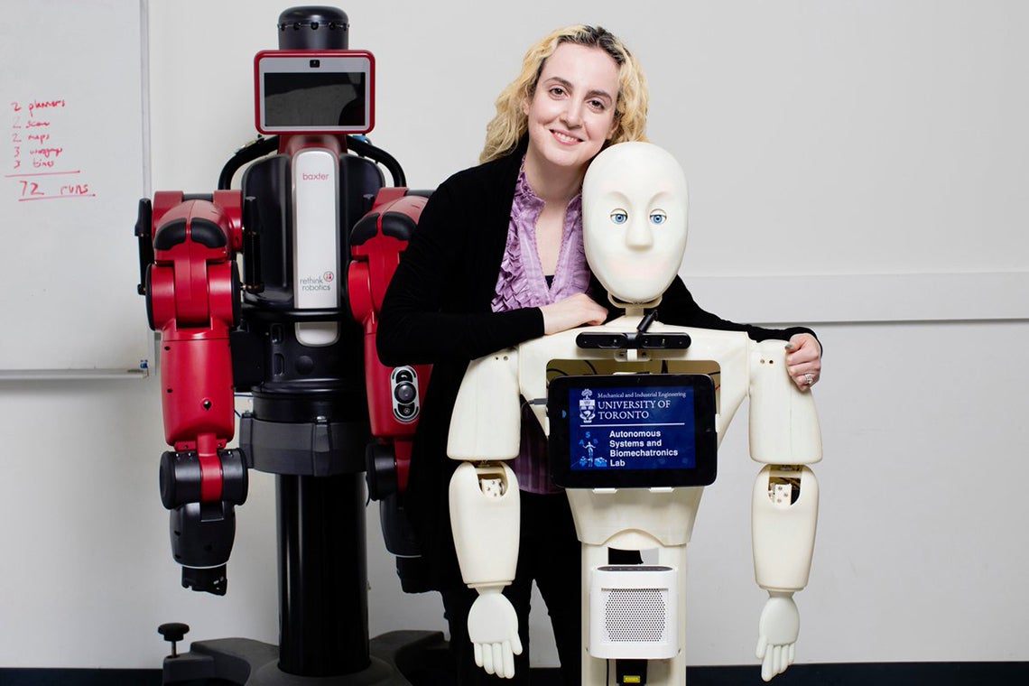Goldie Nejat poses with her robots at the robotics institute