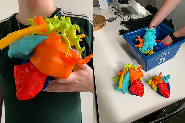 student holding a heart model on the left and a bin of printed heart parts on the right
