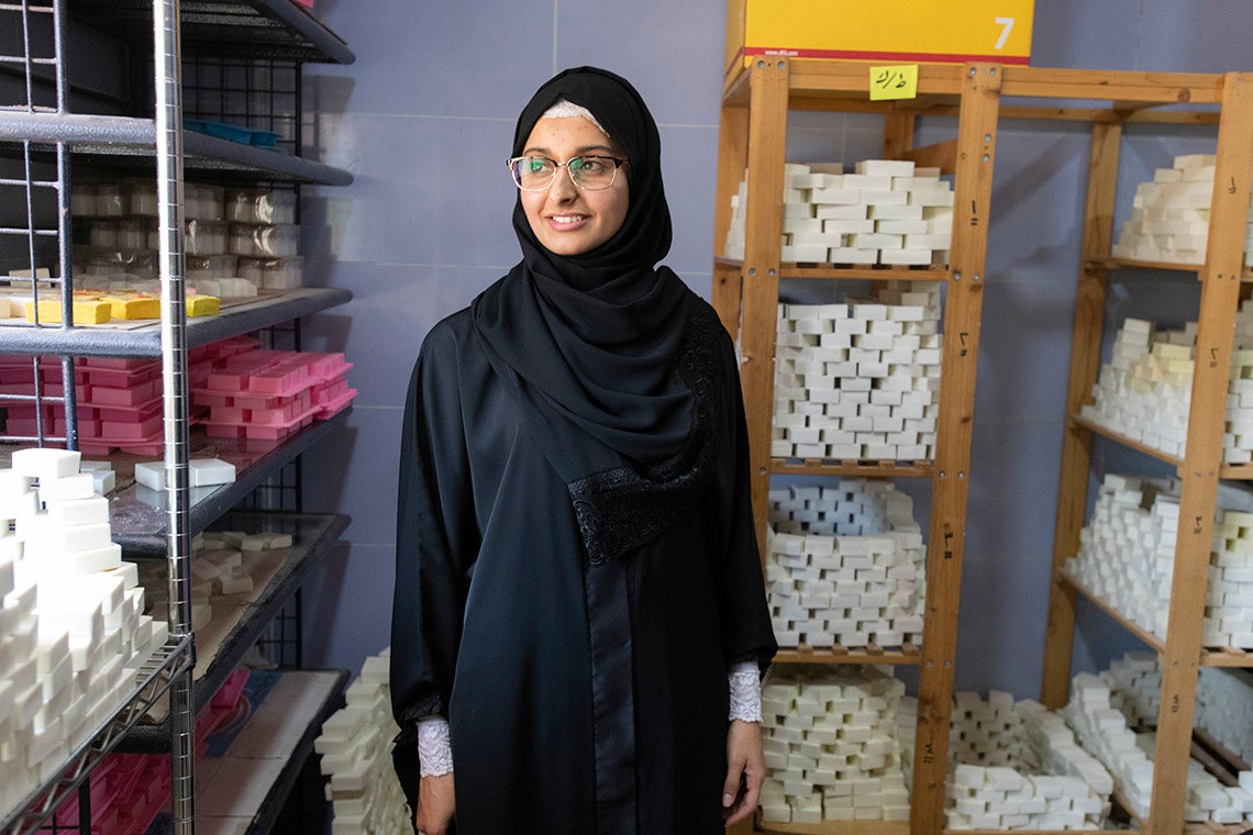 a Jordanian sitti soap employee stands in a storeroom surrounded by bars of soap