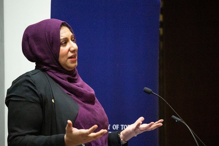 Ausma Malik stands in front of a microphone