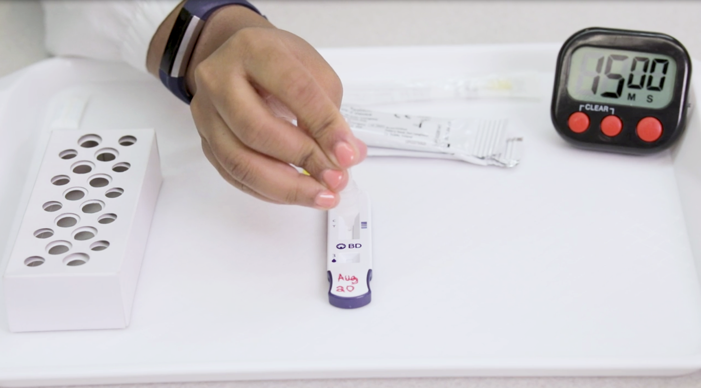 A hand operates an antigen rapid test.