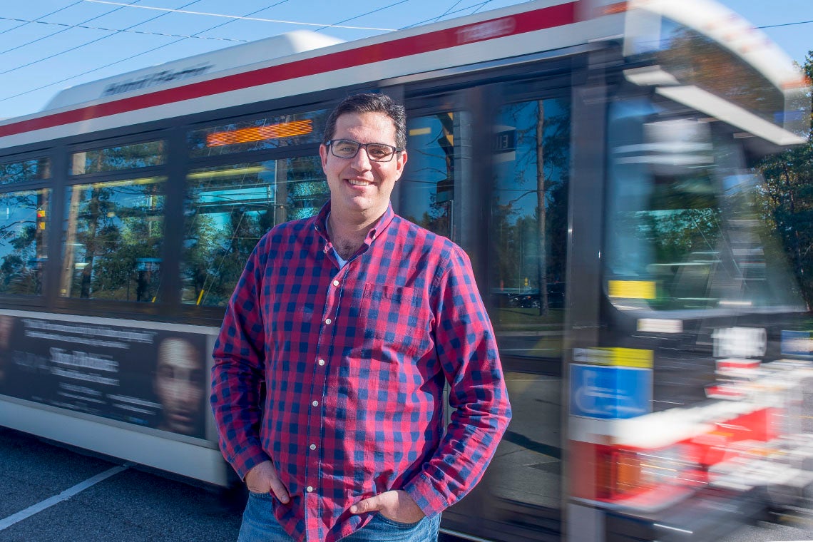 Steven Farber outside with a bus passing behind him