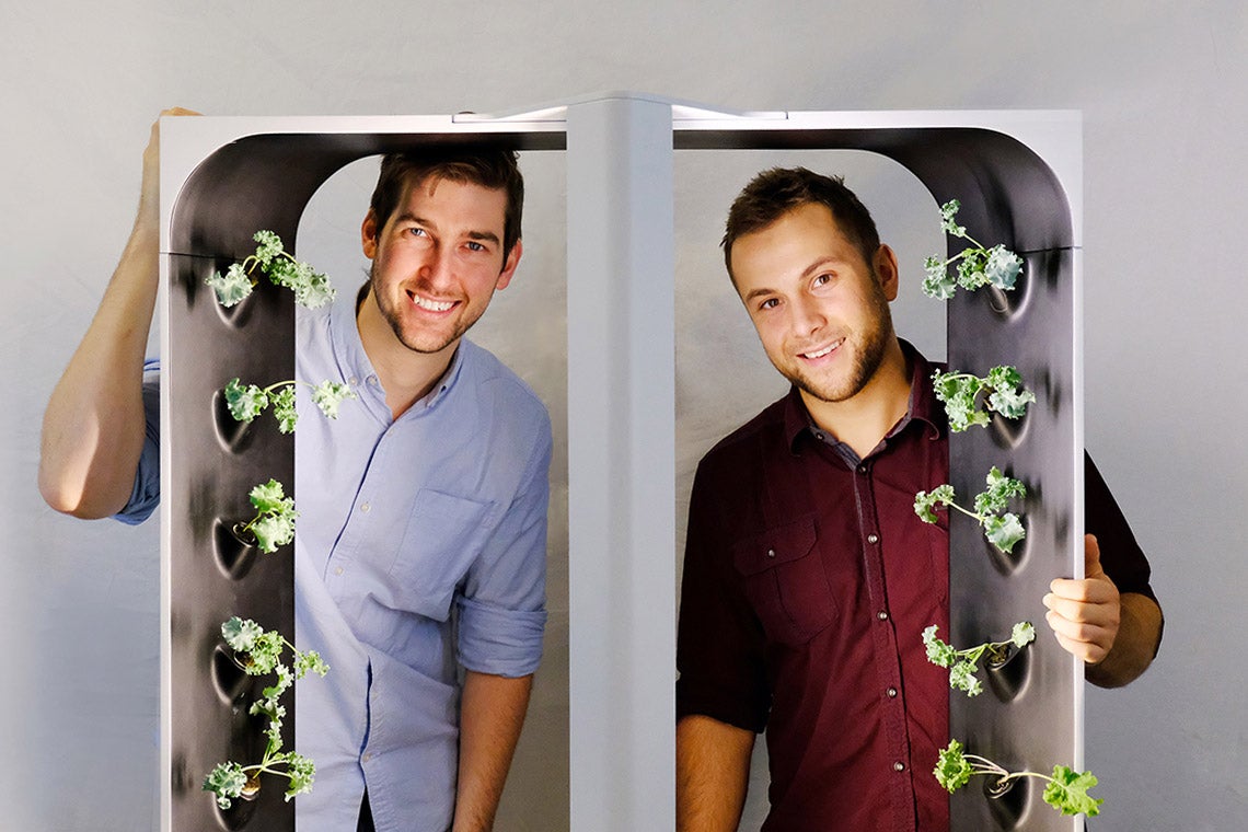 Conner Tidd and Kevin Jakiela are pictured looking through one of their hydroponic growing towers