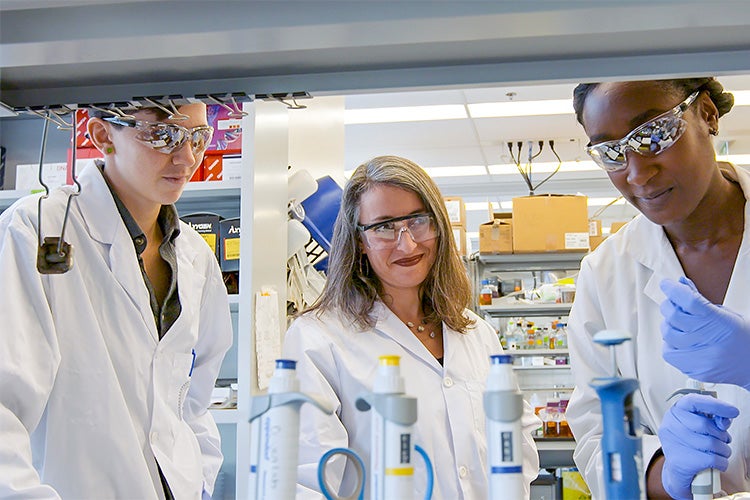 Leah Cowen working with two students in a lab