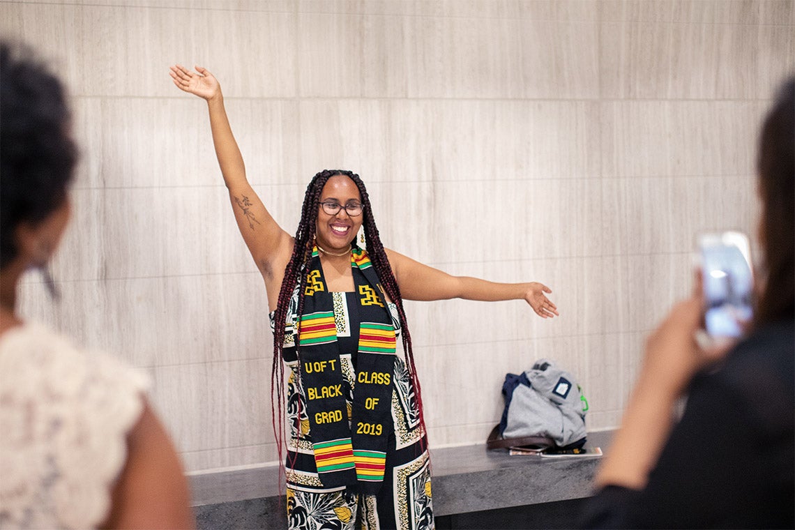 Sarah Edo wears a ceremonial scarf and poses for a photo after the 2019 black graduation ceremony
